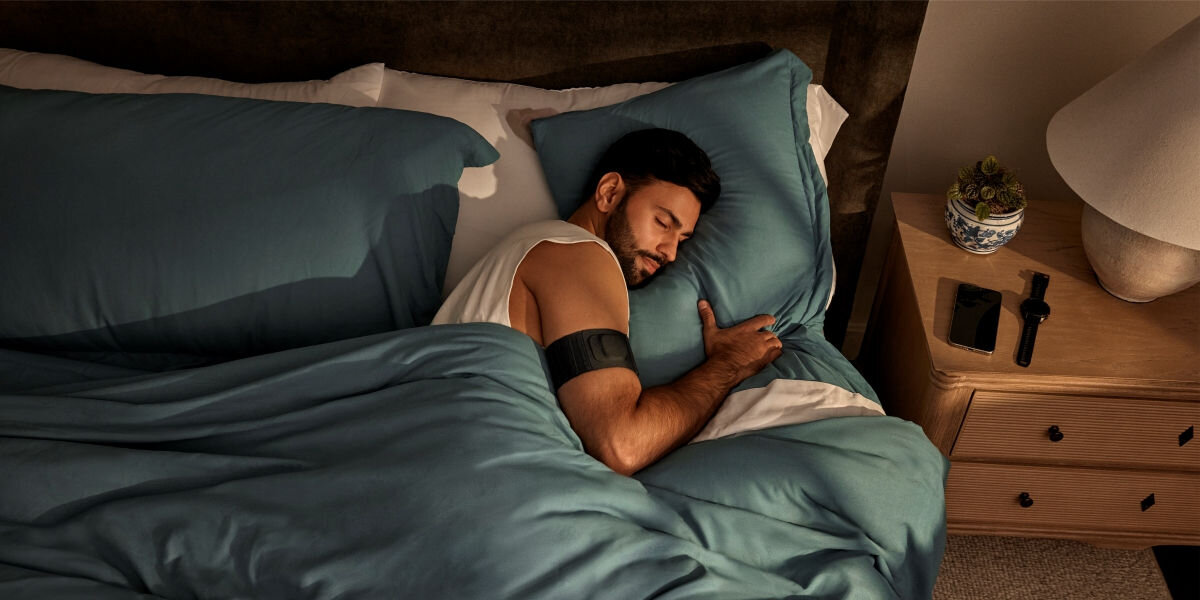 Monitor snu GARMIN Index Sleep (Rozmiar L-XL) Codzienna kontrola jakości snu - śpiąca osoba z monitorem snu w formie opaski na ramieniu