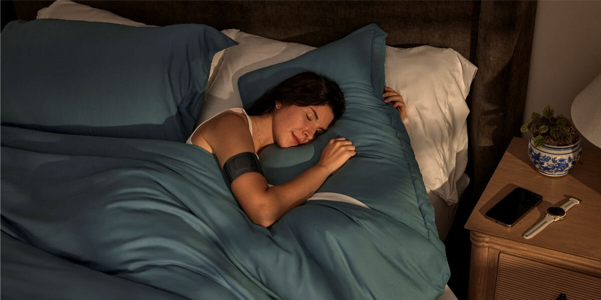 Monitor snu GARMIN Index Sleep (Rozmiar S/M) Codzienna kontrola jakości snu - śpiąca osoba z monitorem snu w formie opaski na ramieniu