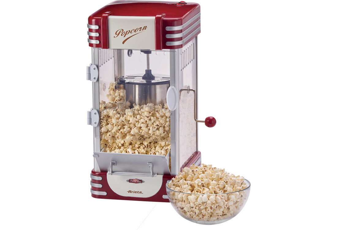 Maszyna do popcornu w stylu retro z czerwonymi i srebrnymi elementami, wypełniona popcornem. Obok znajduje się szklana miska z popcornem, a na maszynie widoczny jest napis \'Popcorn\' oraz logo \'Ariete\'.