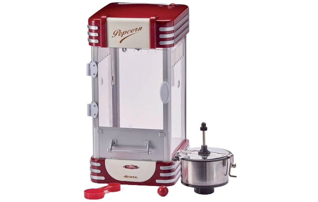 Maszyna do popcornu w stylu retro z czerwonymi i srebrnymi elementami, z przezroczystymi ścianami i napisem \'Popcorn\' na górze. Obok znajduje się metalowy pojemnik z uchwytem oraz czerwona miarka.