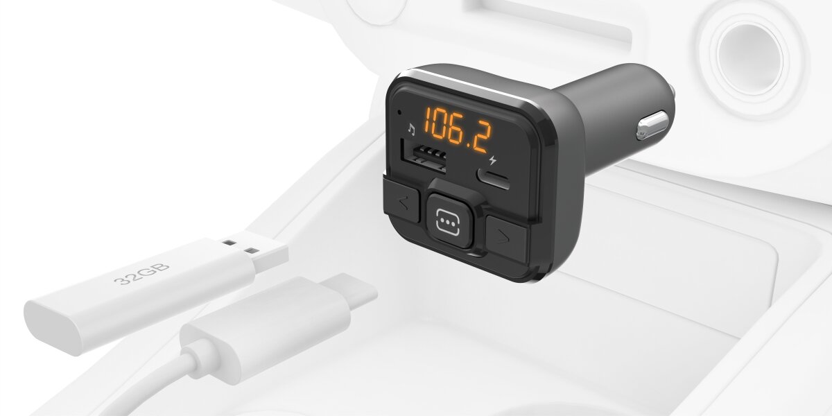 Czarno-szary transmiter FM z wyświetlaczem pokazującym częstotliwość 106.2. Obok znajduje się biały pendrive z napisem \'32GB\'.