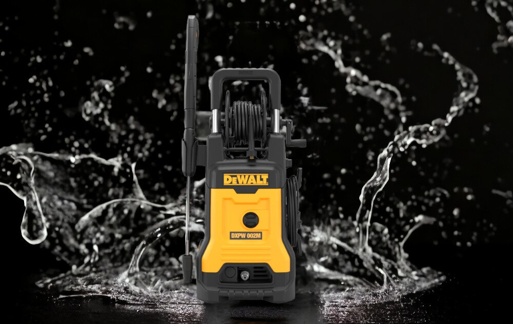 Na obrazie widoczna jest myjka ciśnieniowa z logo DEWALT i oznaczeniem DXPW002M-E, otoczona rozpryskującą się wodą na czarnym tle.