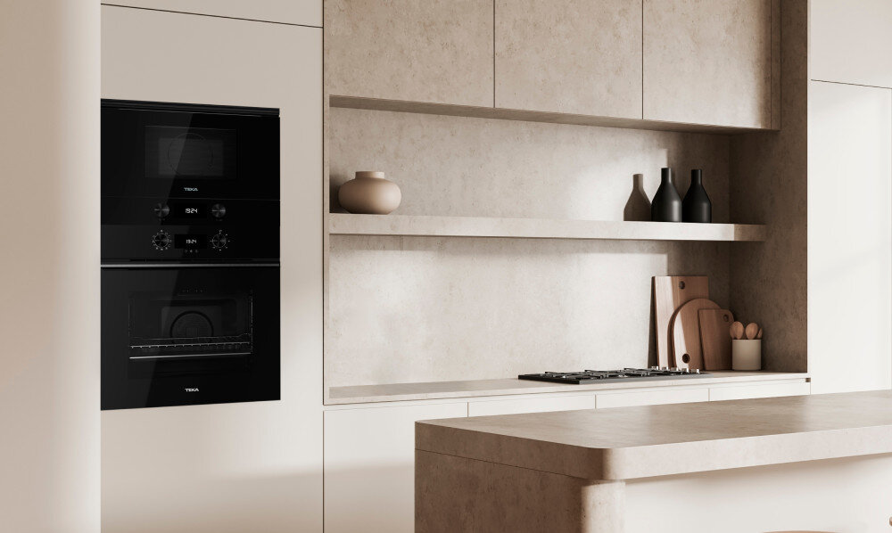 KUCHENKA MIKROFALOWA TEKA ML 820 FI BK Zdjęcie przedstawia jasną, minimalistyczną kuchnię z piekarnikiem i kuchenką mikrofalową TEKA zabudowanymi w wysokiej szafie po lewej stronie. Wnętrze utrzymane jest w beżowych tonach, z kamiennym blatem, otwartą półką i dekoracyjnymi naczyniami minimalistyczny szyk czarne szkło estetyczna połyskująca powierzchnia trendy eleganckie wykończenie