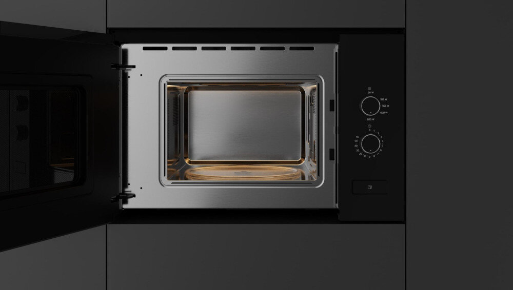 KUCHENKA MIKROFALOWA TEKA ML 820 FI BK Zdjęcie przedstawia otwartą kuchenkę mikrofalową z jasnym, stalowym wnętrzem i delikatnym podświetleniem u dołu, widocznym przez otwarte drzwi. Po prawej stronie znajdują się dwa pokrętła sterowania funkcjami oraz przycisk umieszczony pod panelem clickinstallation montaż łatwość szybkie stabilność estetyka