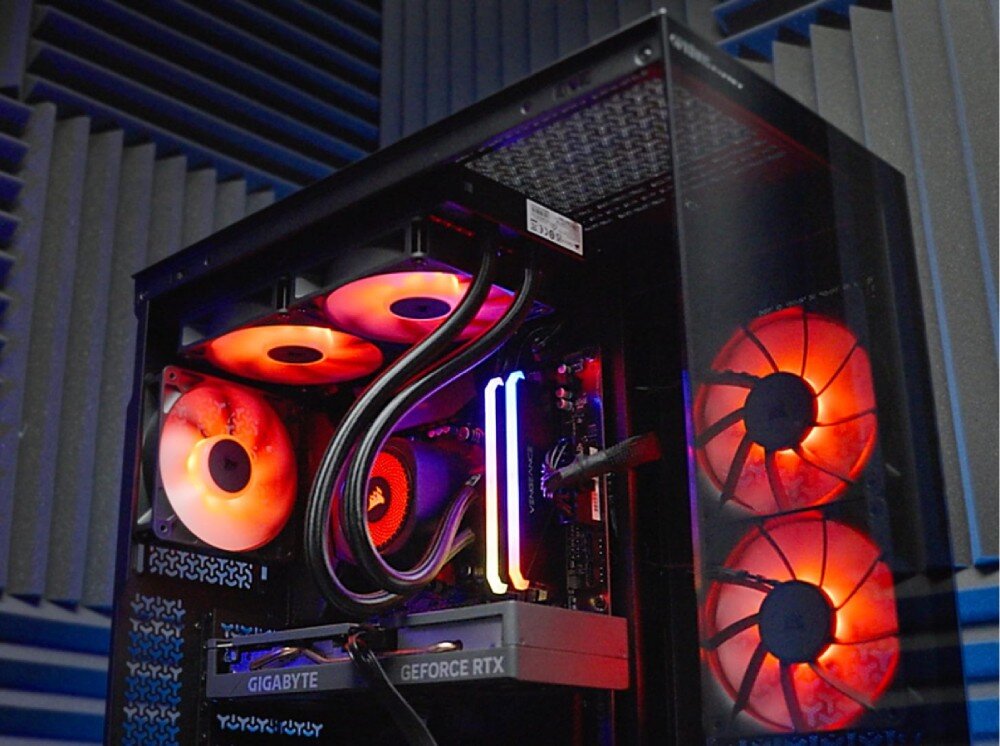 Komputer OPTIMUS E-Sport GB760T-CR17 Wnętrze włączonego komputera z widocznymi podświetlonymi na pomarańczowo wentylatorami, dwoma świecącymi modułami pamięci RAM oraz kartą graficzną z napisem 'GIGABYTE GEFORCE RTX', cechy, podzespoły, przeznaczenie