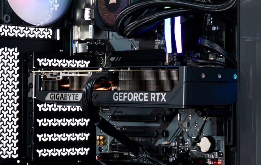 Komputer OPTIMUS E-Sport GB760T-CR17 Zbliżenie na poziomą kartę graficzną z widocznym radiatorem i napisem 'GIGABYTE GEFORCE RTX', zamontowaną na płycie głównej wewnątrz czarnej obudowy, karta graficzna, architektura