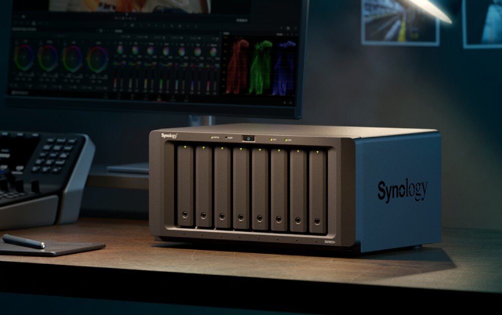 Serwer plików SYNOLOGY DiskStation DS1825+ Urządzenie z kilkoma zatokami dyskowymi stoi na biurku obok monitora, lampki i telefonu, opis