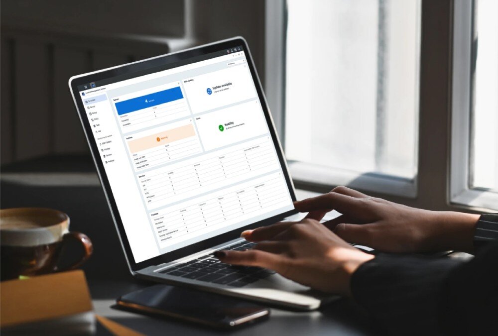 Serwer plików SYNOLOGY DiskStation DS1825+ Osoba korzysta z laptopa z otwartym interfejsem administracyjnym pokazującym status serwera i systemu, kontrola, ustawienia, integracja