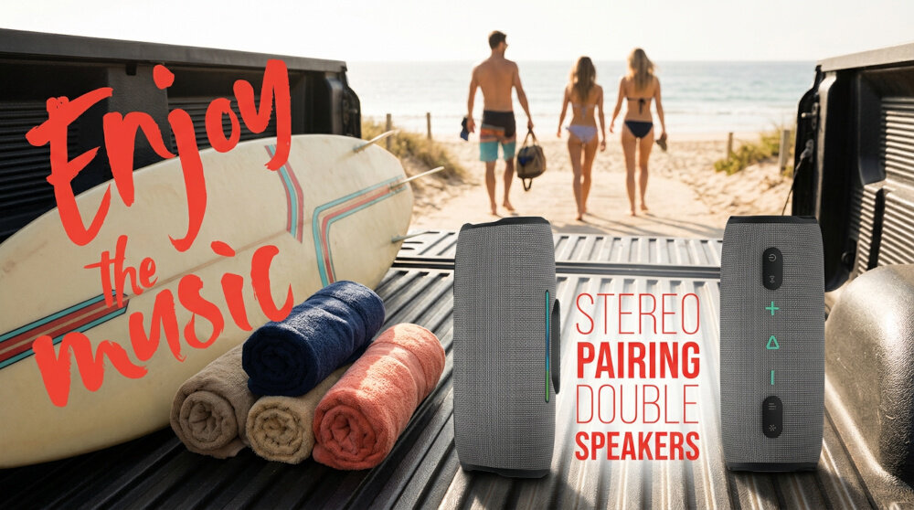 Na obrazie widać dwa szare głośniki mobilne ustawione na pace samochodu, obok ręczników i deski surfingowej. Widoczny tekst to \'Enjoy the music\' oraz \'STEREO PAIRING DOUBLE SPEAKERS\'.