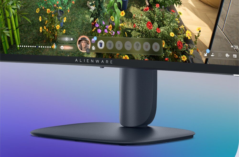 Monitor DELL Alienware AW3225DM Zbliżenie na podstawę i dolną ramkę monitora z logo marki, na ekranie widać fragment gry z roślinnością