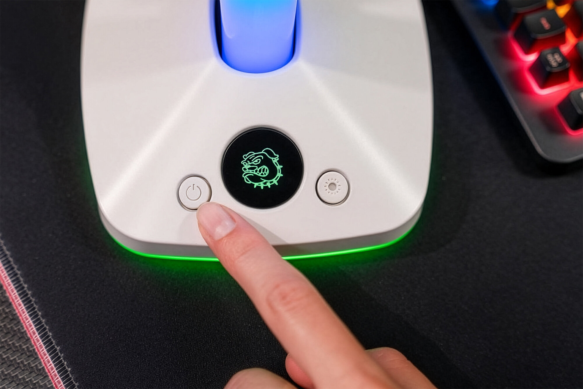 MAD DOG HPS800W Zbliżenie na białą podstawę stojaka MAD DOG. Palec naciska przycisk zasilania, obok widoczne jest podświetlane logo MAD DOG i przycisk zmiany trybu oświetlenia