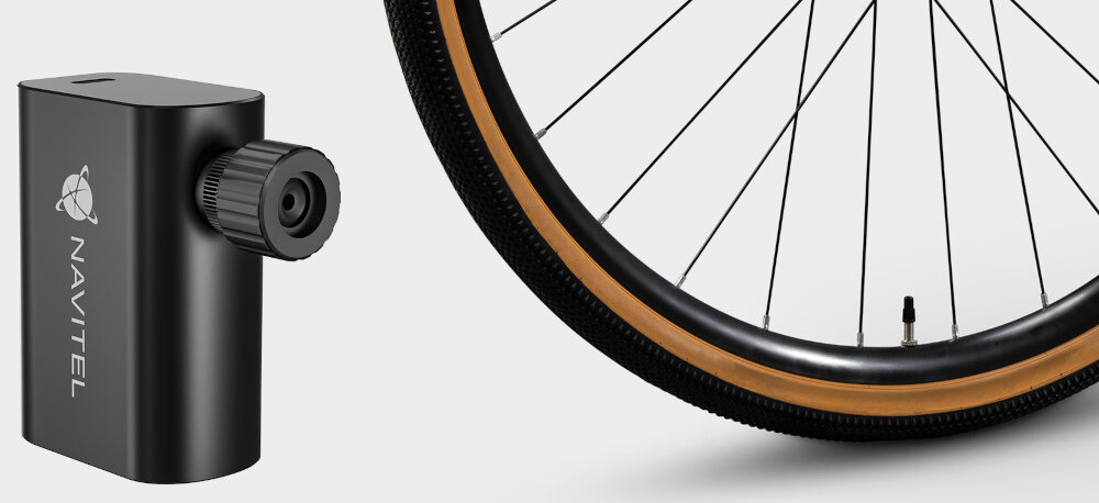 Pompka rowerowa NAVITEL Air12 Mini jasne tło pompka na zdjęciu obok koło od roweru wydajność do 12 litrów powietrza na minutę maksymalne ciśnienie do 120 PSI (~8 bar) w codziennym użytkowaniu w wymagających warunkach terenowych