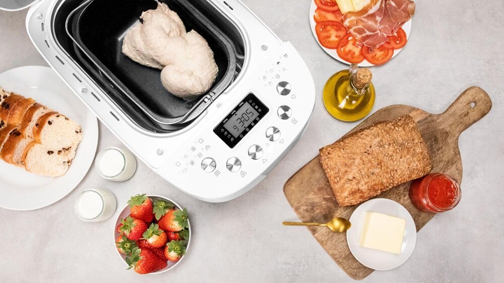 Wypiekacz do chleba CECOTEC Chleb&Co 1500 PerfectCook urządzenie z góry na blacie kuchennym w otoczeniu wypieków, wysoka moc, kontrola składu wypieków