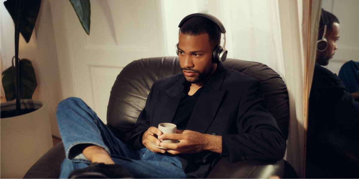 Nagrodzony design, wysokiej jakości materiały, wymienne nauszniki, składana konstrukcja, osoba siedząca na fotelu z założonymi słuchawkami nausznymi