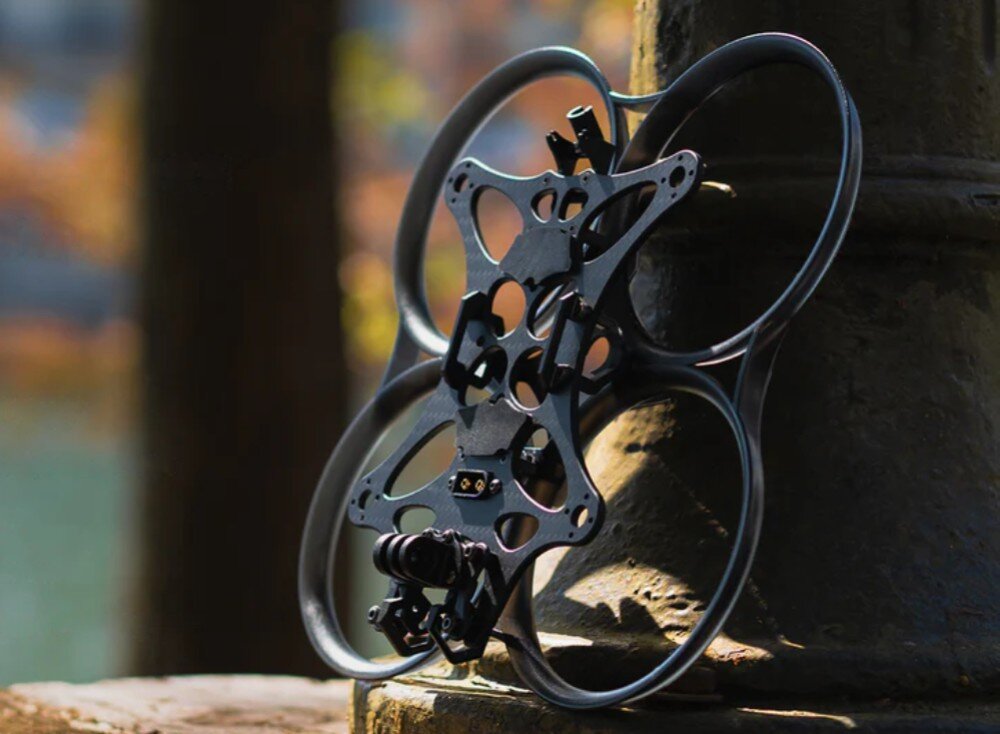 Dron BETAFPV Pavo35 Szkielet drona z widocznymi elementami z włókna węglowego i aluminium oparty o metalowy słup