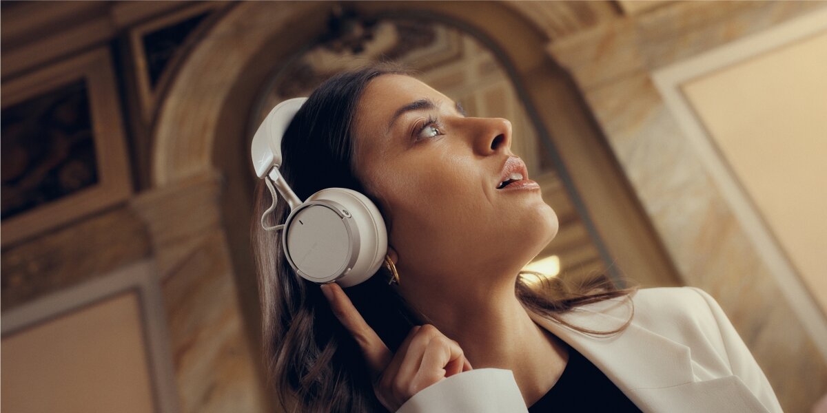 Nagrodzony design, wysokiej jakości materiały, wymienne nauszniki, składana konstrukcja, osoba siedząca na fotelu z założonymi słuchawkami nausznymi