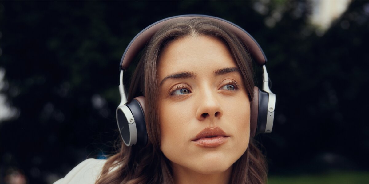 Nagrodzony design, wysokiej jakości materiały, wymienne nauszniki, składana konstrukcja, osoba siedząca na fotelu z założonymi słuchawkami nausznymi