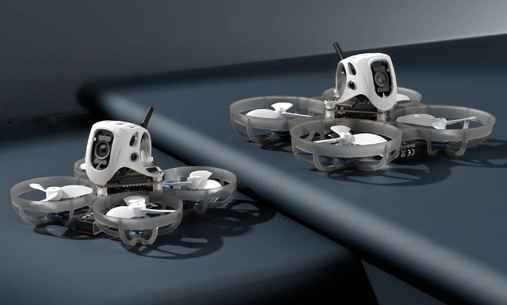 Dron BETAFPV Meteor75 Pro O4 Dwa małe drony wyścigowe w kolorze białym ustawione jeden za drugim na ciemnoniebieskiej pofalowanej powierzchni