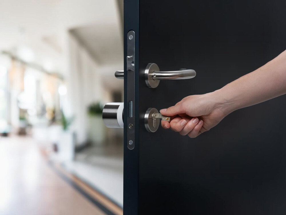 Zamek NUKI Smart Lock Ultra, wkładka, certyfikat, ochrona, bezpieczeństwo, Dłoń przekręca tradycyjny klucz w zamku drzwi.