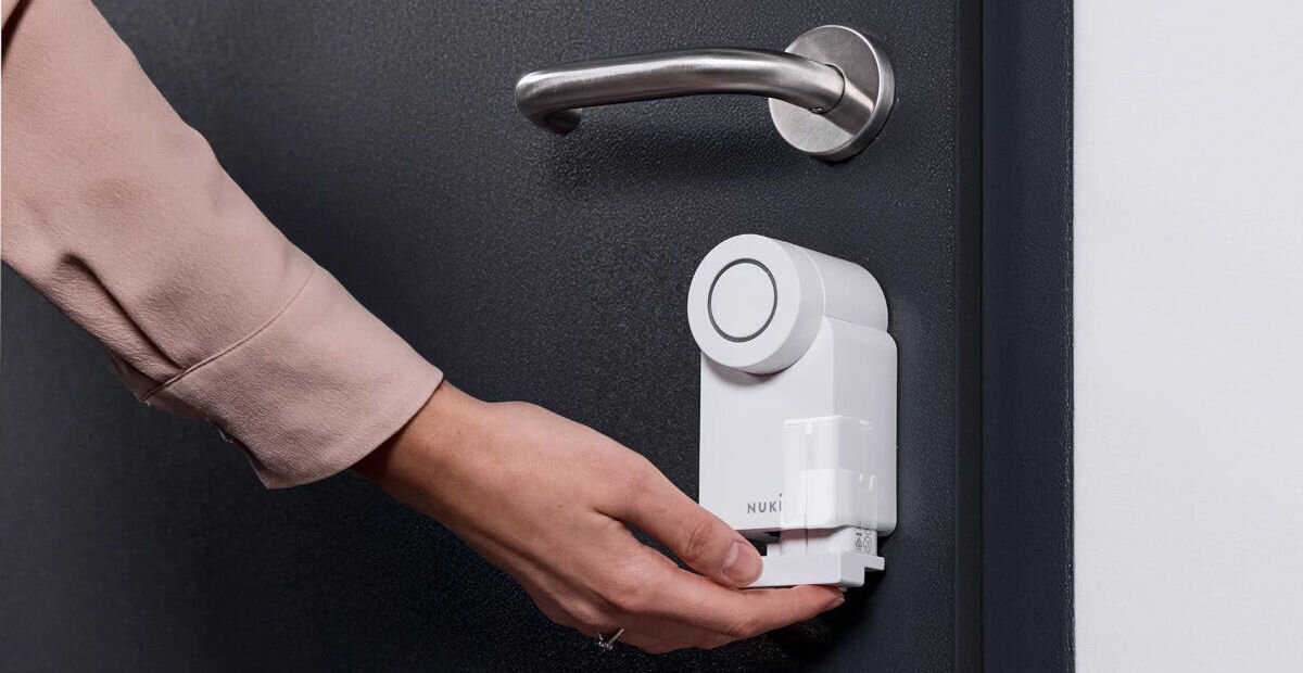 Zamek Nuki Smart Lock Go, wkładka, awaria, wiercenie, specjalistyczne, dłoń chwyta od spodu zamek zamontowany do drzwi