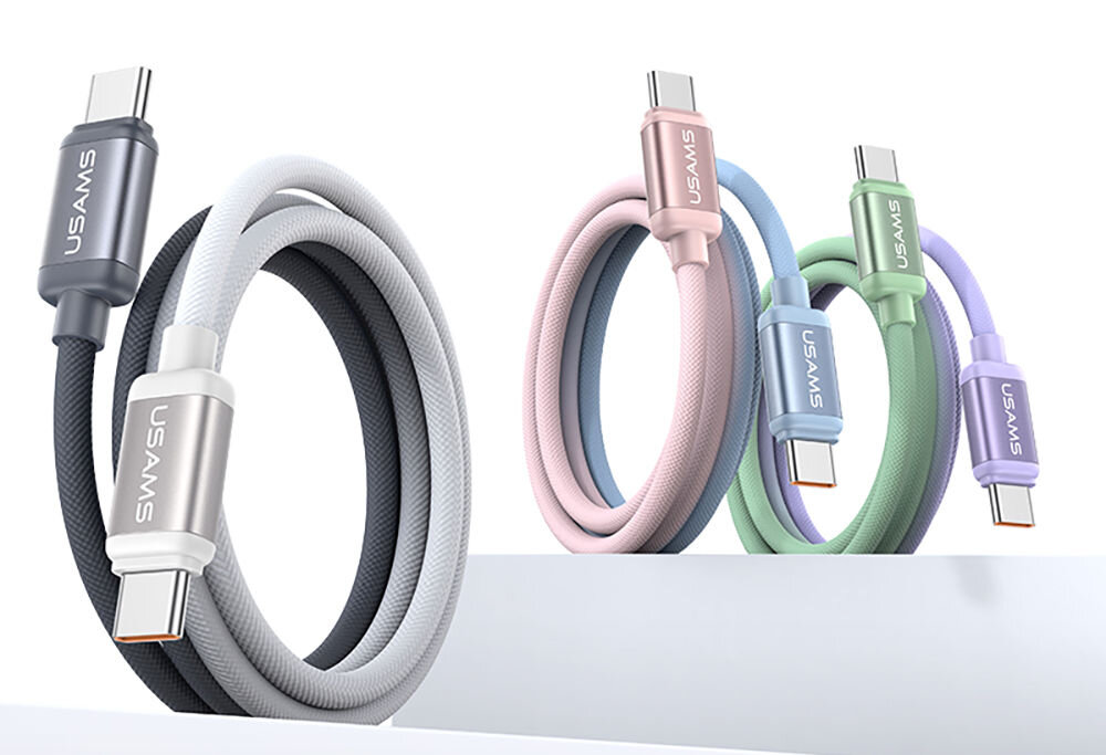 Na obrazie widoczne są cztery kable USB-C w różnych kolorach: czarno-biały, różowy, niebieski i zielony, z logo \'USAMS\' na złączach. Kable są zwinięte i ustawione na białej powierzchni.