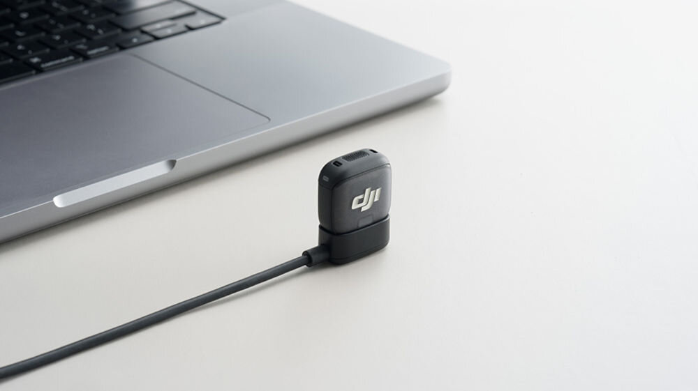 Nadajnik DJI Mic 3 prezentacja nadajnika podłączonego do kabla obok laptop na jasnym tle nadajnik i odbiornik z długim czasem pracy i szybkim ładowaniem czas ładowania etui ładujące tryby oszczędzania energii automatyczne wyłączanie komfort