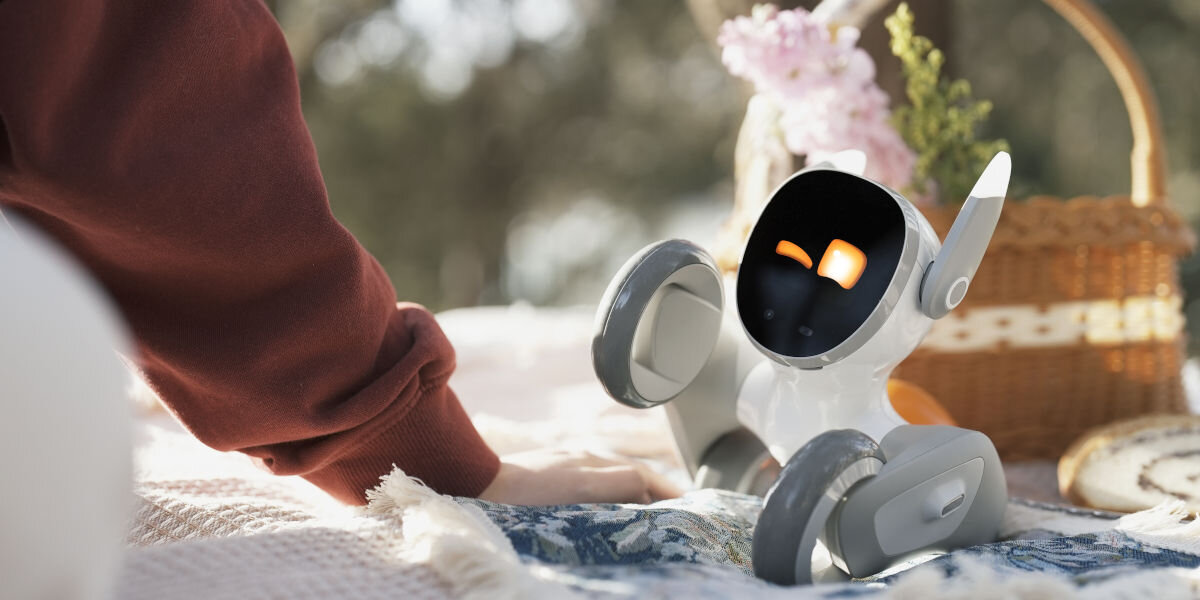 Zabawka interaktywna KEYI TECH Robot Loona Premium Edition KY004LN01 robot z podniesioną łapką na kocu w tle kosz piknikowy