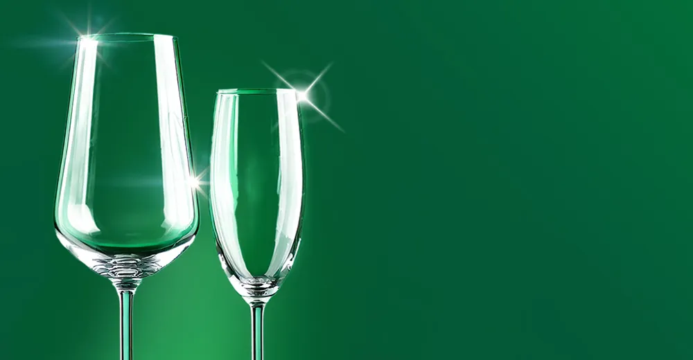 Kieliszek do wina i kieliszek do szampana, błyszczące od czystości na zielonym tle.