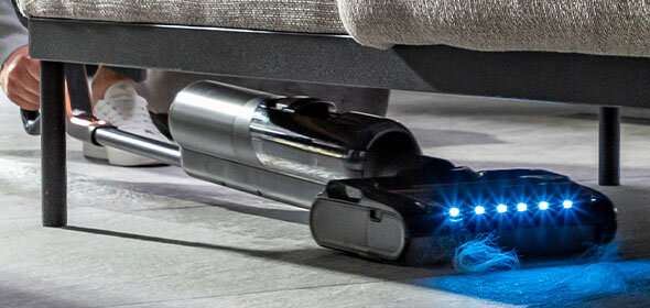 Bezprzewodowy odkurzacz X-CLEAN 7 z diodami LED zbiera sierść spod mebla.