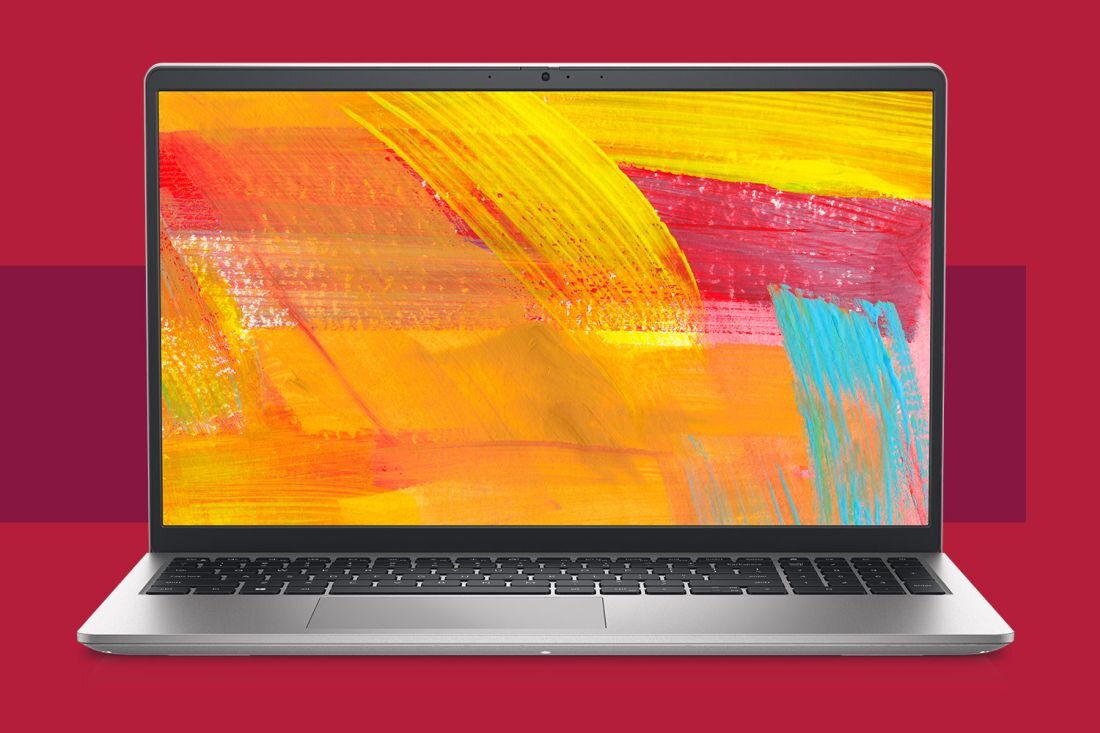 Laptop z wyświetlaczem prezentującym kolorowe, abstrakcyjne tło w odcieniach żółci, czerwieni i błękitu. Obudowa laptopa jest srebrna, a tło obrazu jest czerwone.