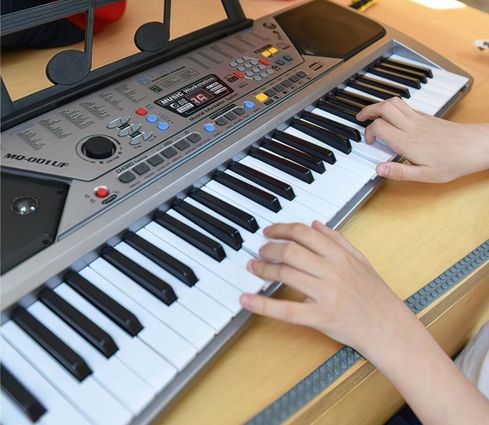 Osoba gra na elektronicznej klawiaturze z widocznym napisem \'MD-001 UF\'. Klawiatura posiada wiele przycisków funkcyjnych i wyświetlacz cyfrowy.