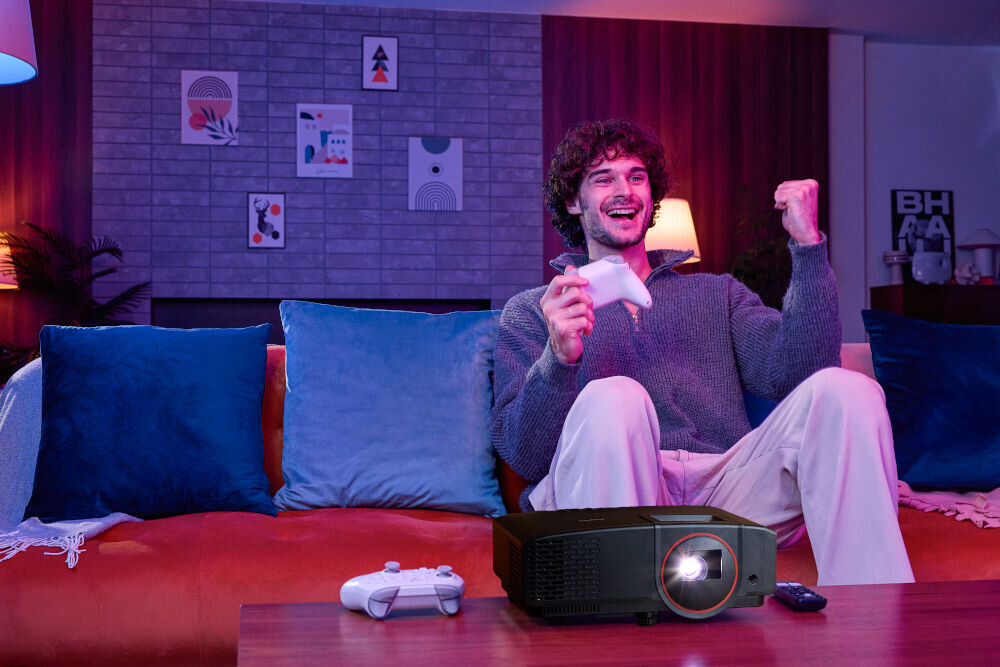 Projektor PHILIPS GamePix 800 porty HDMI USB-A audio RS-232, osoba siedząca na sofie, grająca w gry, projektor wyświetlający obraz