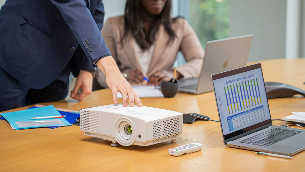 Projektor PHILIPS ProPix 650 z HDMI, D-Sub, USB i RS-232 do podłączenia wielu urządzeń, projektor stojący na biurku, osoby uczestniczące w spotkaniu biznesowym