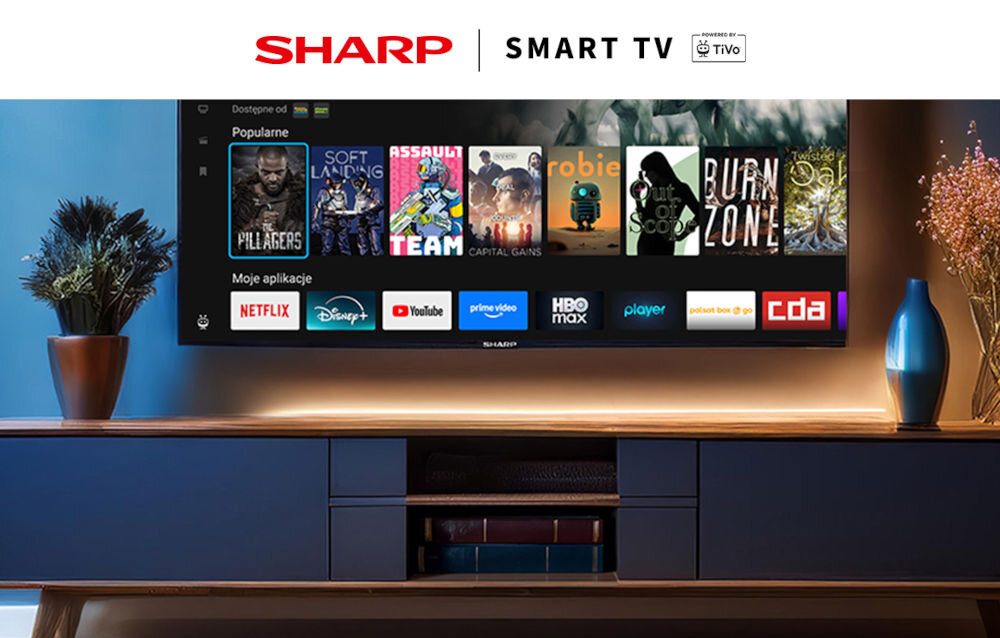 Telewizor SHARP 32HE2745E system TiVo filmy seriale jedna lista, telewizor zawieszony nad komodą w pomieszczeniu