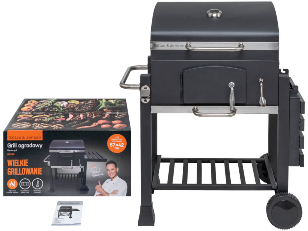 Grill węglowy GÖTZE & JENSEN GG700 56.5 x 41.8 cm Czarny grill węglowy Götze & Jensen GG700 z termometrem w pokrywie, obok oryginalnego opakowania z wizerunkiem kucharza i instrukcji obsługi.