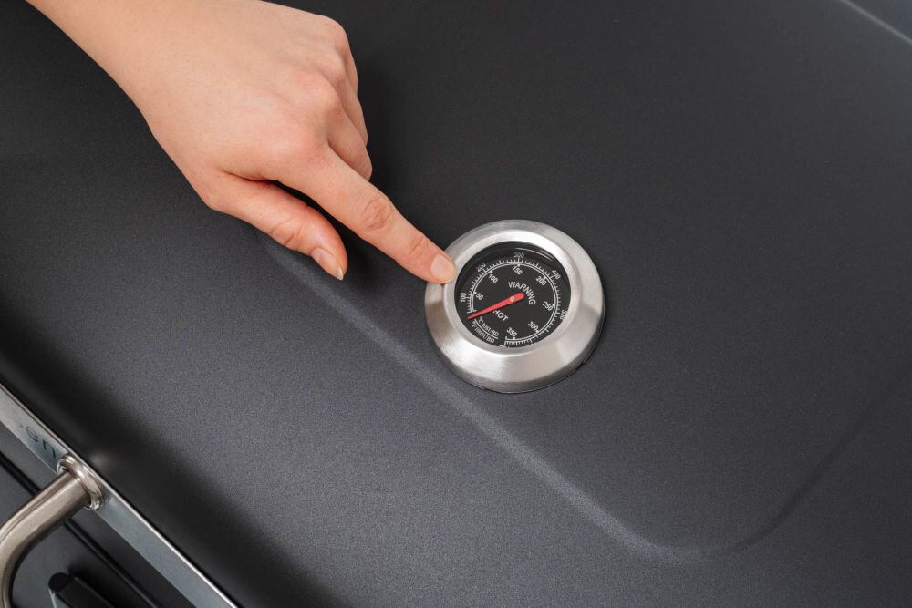 Grill węglowy GÖTZE & JENSEN GG710 z kominem 56.5 x 41.8 cm Zbliżenie na wbudowany w pokrywę termometr tarczowy ze skalą Celsjusza i Fahrenheita, wskazujący temperaturę wewnątrz grilla.