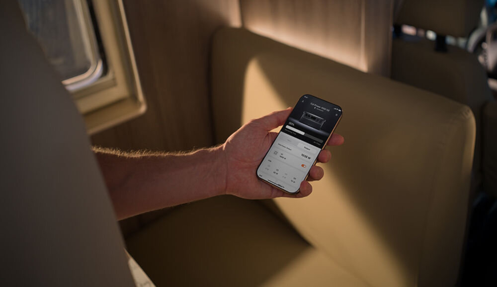 Stacja zasilania DJI 1000 V2 1024Wh Bank energii, aplikacja, android, ios, zdalne, osoba trzyma w dłoni smartfon z włączoną aplikacją DJI Home