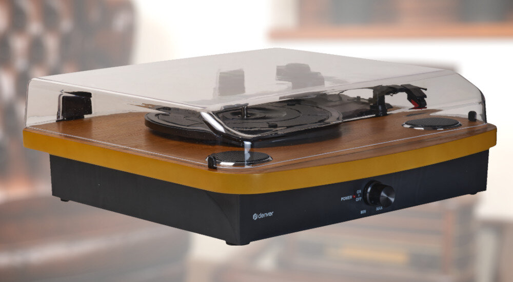 Gramofon z drewnianą obudową i przezroczystą pokrywą, z widocznymi elementami sterującymi i logo \'denver\'.