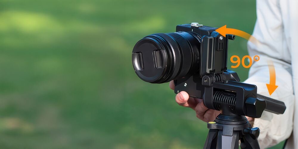 Męska dłoń ustawia lustrzankę na statywie K&F Concept S254A3 z głowicą BV01 na tle zieleni