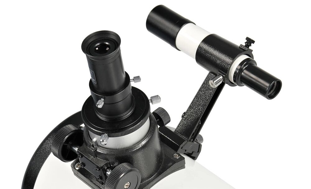 Obraz przedstawia górną część teleskopu z widocznym okularowym wyciągiem i celownikiem. Teleskop ma czarną i białą kolorystykę z metalowymi elementami regulacyjnymi.