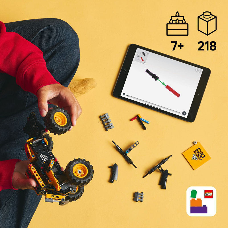 Osoba trzyma model pojazdu z dużymi kołami z klocków LEGO na żółtym tle. Obok leży tablet z instrukcją oraz kilka rozłożonych elementów LEGO, a w rogu widoczne jest logo LEGO.