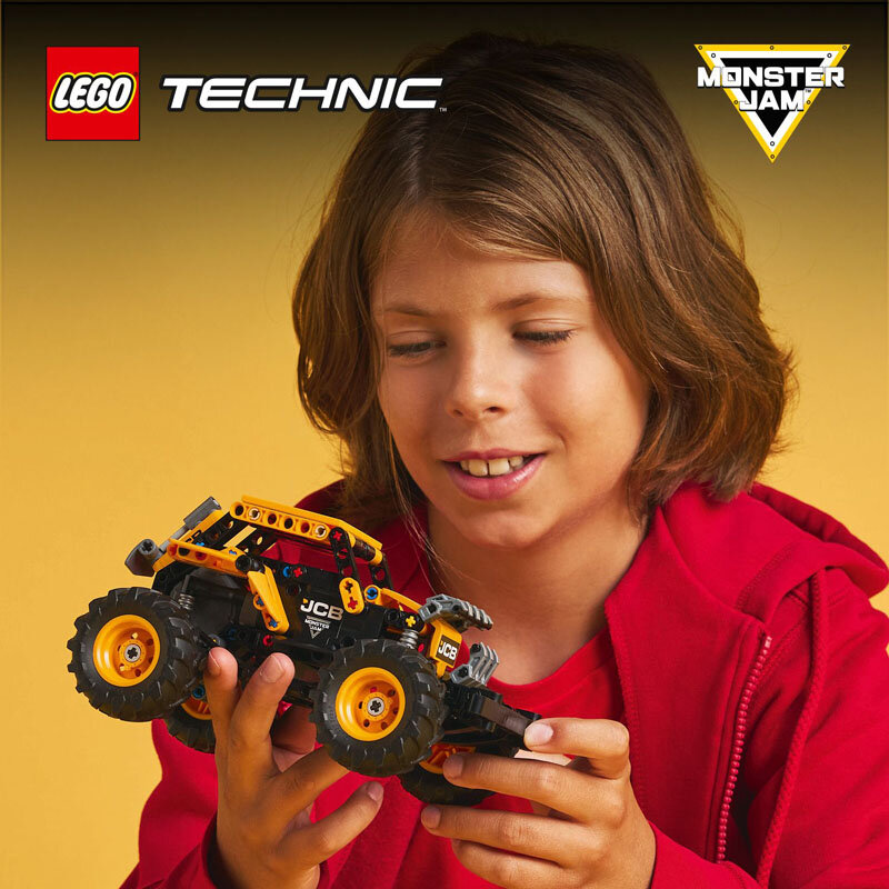 Osoba trzyma model pojazdu z dużymi kołami, zbudowany z klocków LEGO. Widoczne są logotypy LEGO, TECHNIC i MONSTER JAM.