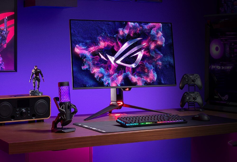 Monitor ASUS ROG Swift PG32UCDMR Stanowisko gracza z monitorem na drewnianym biurku, obok mikrofon z fioletowym podświetleniem, klawiatura i głośnik, panel QD-OLED, rozdzielczość, przekątna, odświeżanie