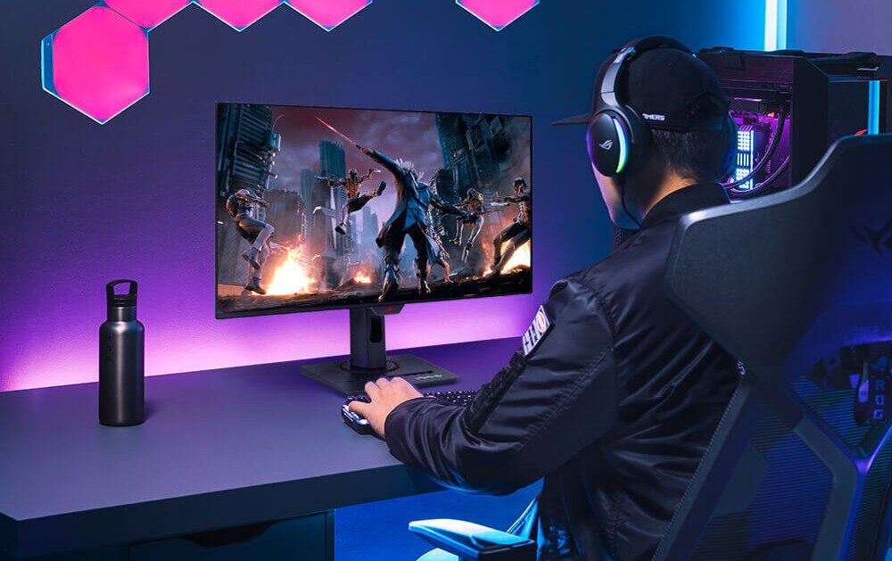 Monitor ASUS ROG Strix XG27AQDPG Gracz siedzący w fotelu gamingowym tyłem do widza, korzystający z monitora, na którym wyświetlana jest dynamiczna scena walki w mieście, stanowisko jest oświetlone fioletowym światłem LED, kolory, odwzorowanie barw, głębia, jasność