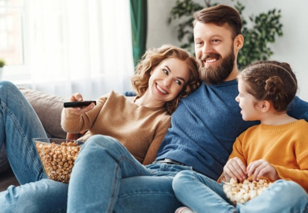 Telewizor PANASONIC TB-55W61AEZ Smart TV TiVo rekomendacje treści, rodzina siedząca na kanapie zajadająca popcorn