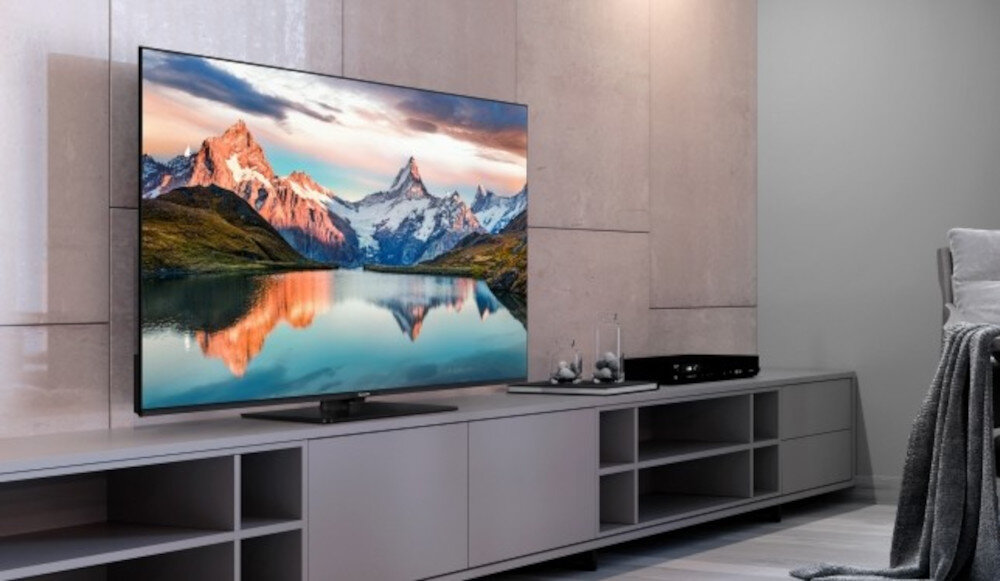 Telewizor PANASONIC TB-55W61AEZ bezramkowy design smukła konstrukcja, telewizor stojący na komodzie w pomieszczeniu