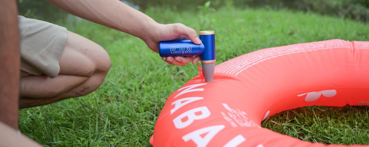 Dmuchawa wielofunkcyjna KICA Jetfan 2S Niebieski, Męska dłoń pompuje czerwone koło do pływania niebieską dmuchawą wielofunkcyjną KiCA Jetfan 2S, ergonomiczna, powietrze, porządek, sprzątanie