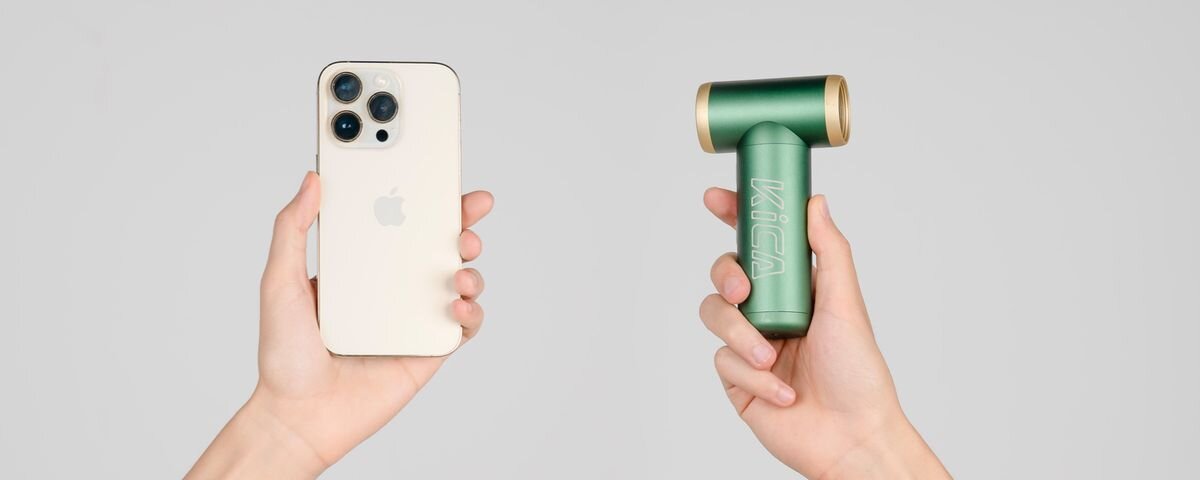 Dmuchawa wielofunkcyjna KICA Jetfan 2S Zielony, Dwie dłonie na szarym tle. W prawej zielona dmuchawa KiCA Jetfan 2S. W lewej dla porównania gabarytów telefon komórkowy, 117000obr, 27,5m/s, aluminum, końcówki