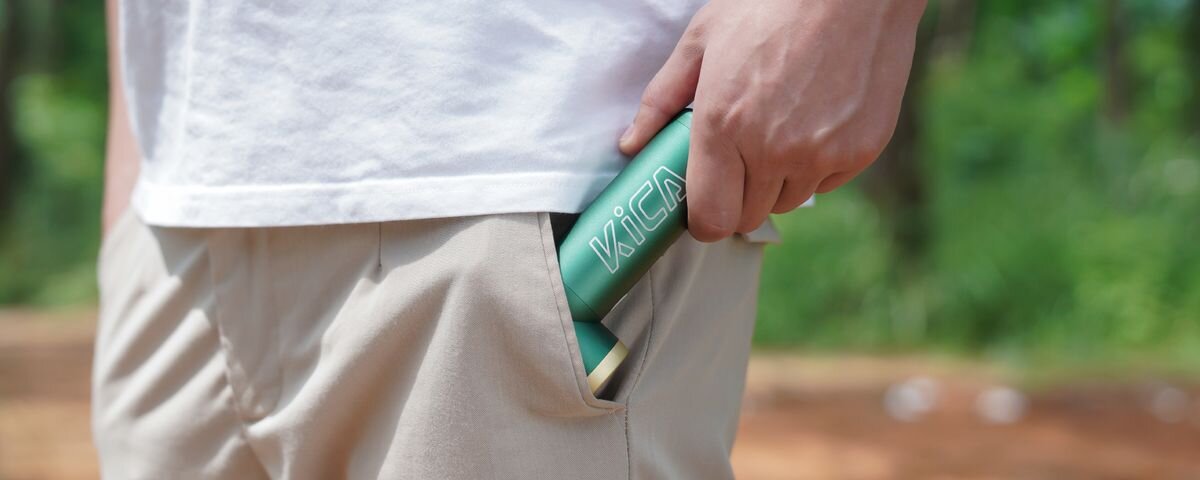 Dmuchawa wielofunkcyjna KICA Jetfan 2S Zielony, Zbliżenie na dłoń mężczyzny wyjmującego zieloną dmuchawę KiCa Jetfan 2S z kieszeni beżowych spodni, 301 g, kurtka, plecak, biwak