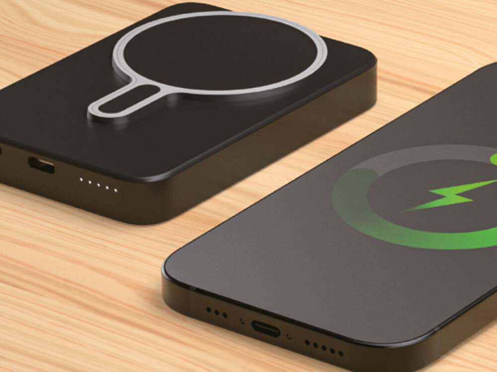 Powerbank XLINE MagSystem 10000 mAh 20W Qi Szary Ciemny powerbank magnetyczny (MagSafe-kompatybilny) z metalicznym pierścieniem do ładowania bezprzewodowego, leżący obok smartfona z ekranem pokazującym zielony wskaźnik ładowania.